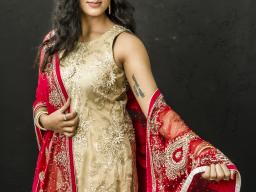 Image of a woman, Mannie Kaur Verma, wearing a gold dress with red shawl.
