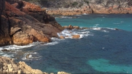 An image of a rocky shoreline with blue seawater.